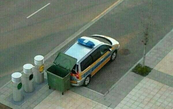 Coche patrulla con radar bajo la tapa de un contenedor de basura